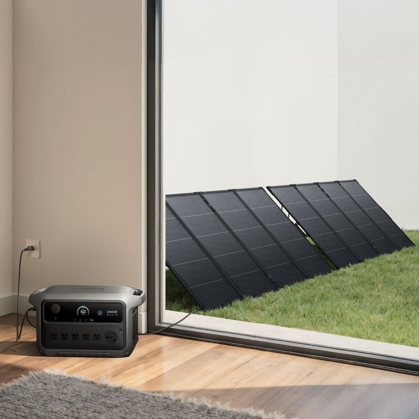 Anker SOLIX C2000 Gen 2 Portable Power Station next to a window with solar panels on a grassy area outside.