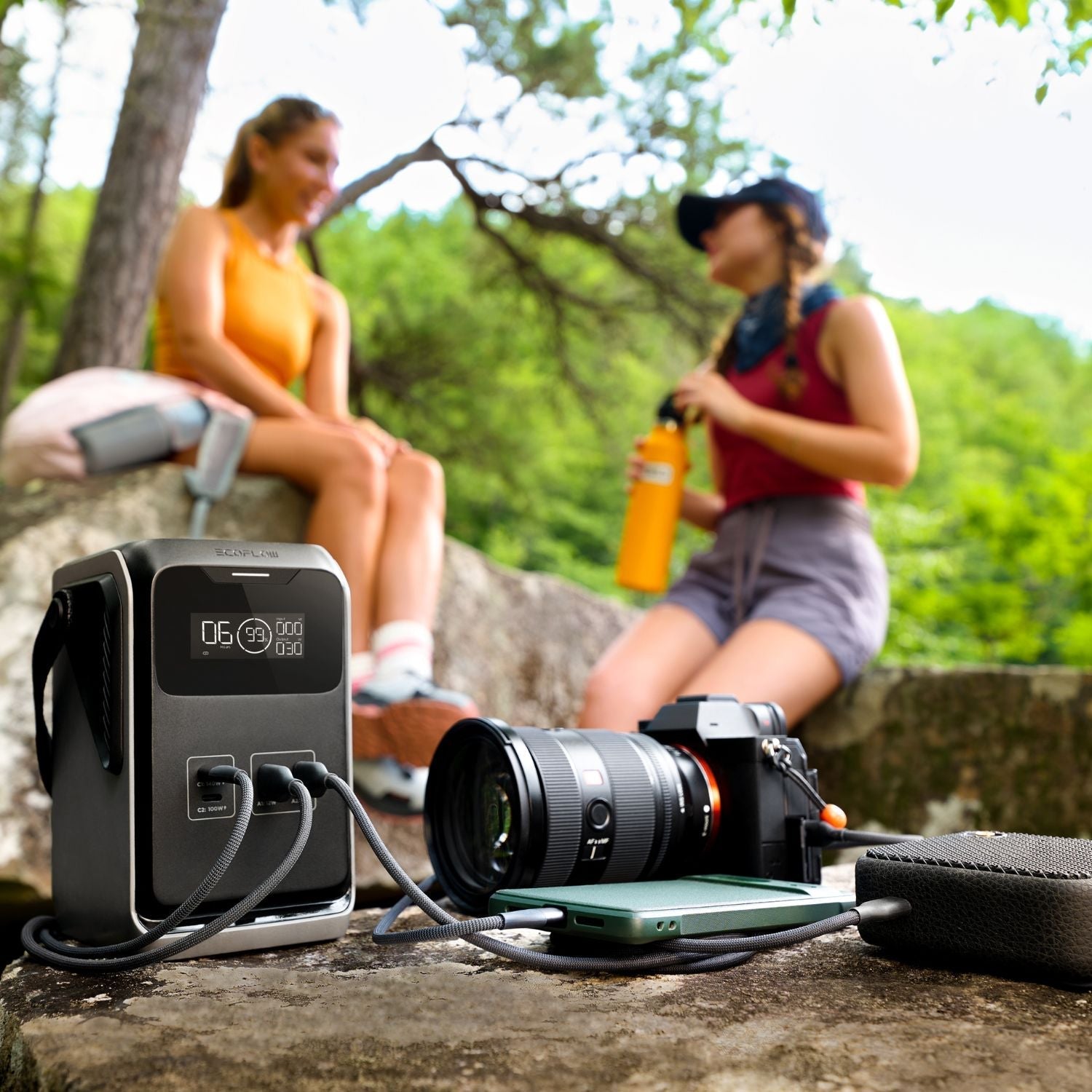 Camera and EcoFlow TRAIL 200DC Portable Power Station on a rock with two people in the background